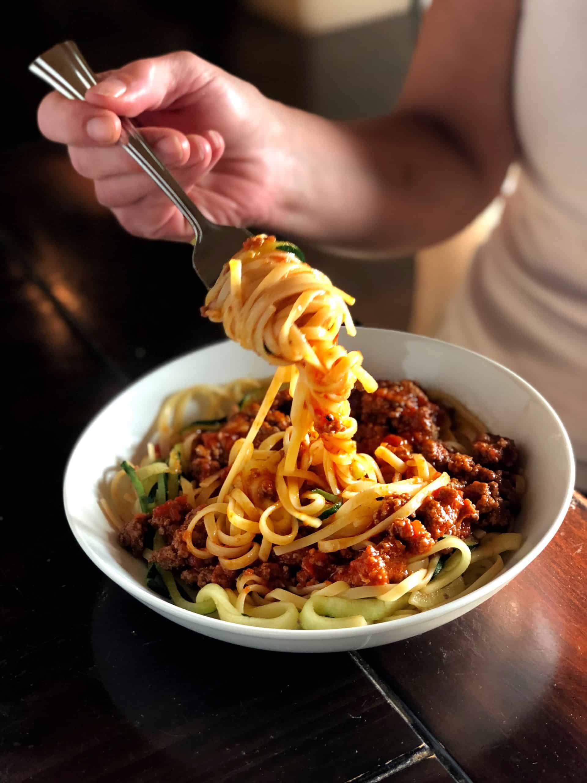 Pork bolognese mixed with zucchini in a white bowl
