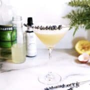 A martini with lemon juice and lavender sprigs.