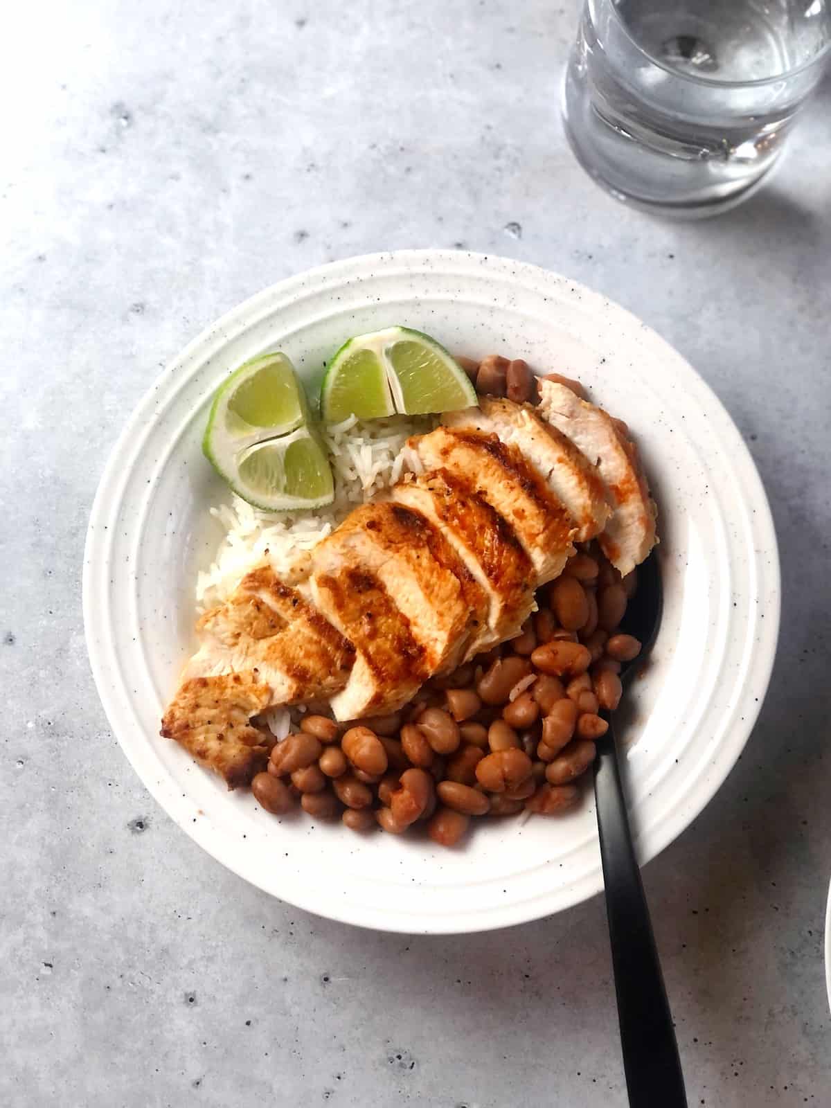 Grilled chicken and beans over rice in a bowl.