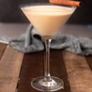 A baileys and eggnog cocktail with a cinnamon stick on top.