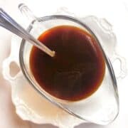 A bowl of sauce with a spoon in it.