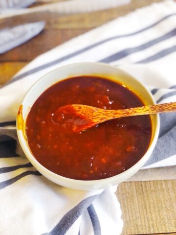 Cherry BBQ sauce in a bowl on a wood board.