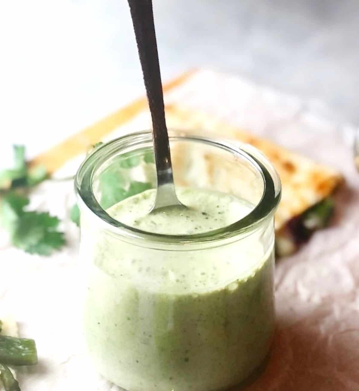 creamy poblano sauce in a container with a spoon.